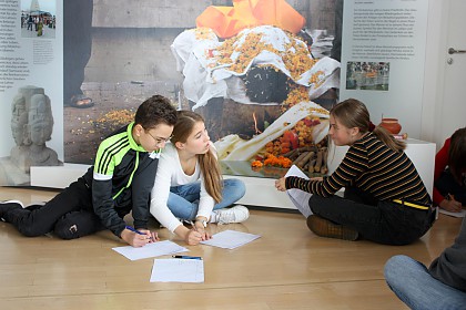 Eine Schulgruppe arbeitet zu den verschiedenen religiösen Bestattungsriten in der Dauerausstellung