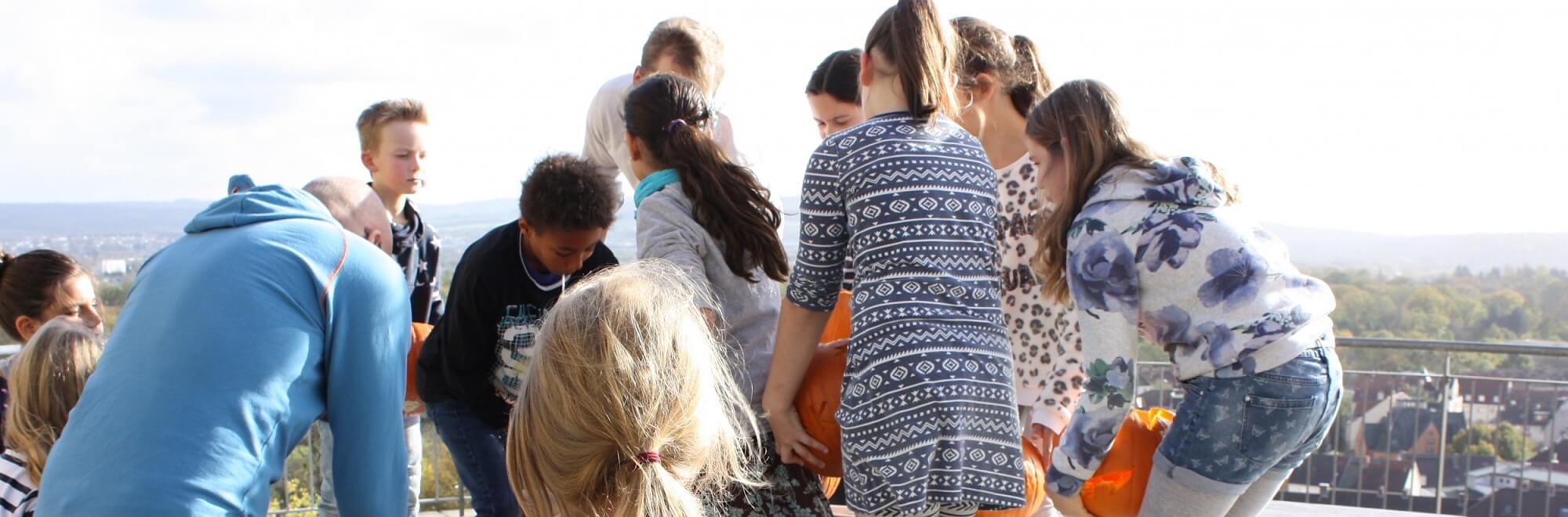 Gruppe von Kindern und Jugendlichen steht im Kreis auf einer Dachterrasse