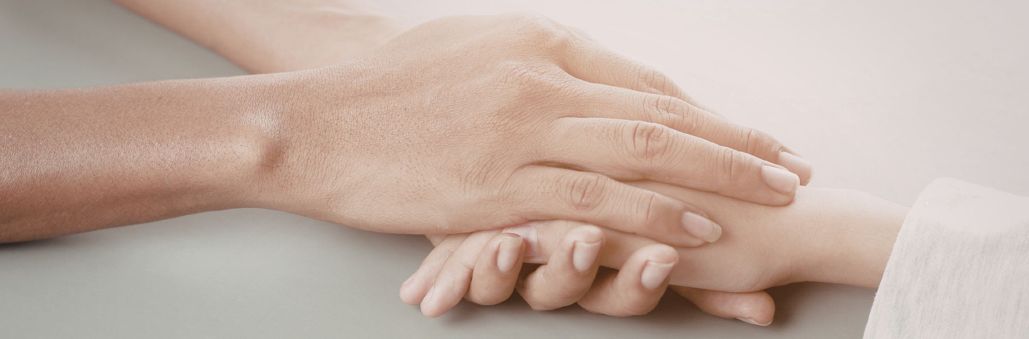 Eine Frau hält zwischen ihren Händen die Hand einer anderen Person