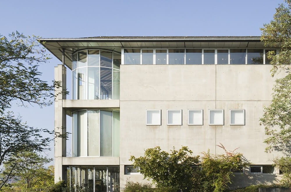 Moderne Außenfassade des Sepukralmuseums mit großen Fenstern, flachem Dach und umgebenden Bäumen