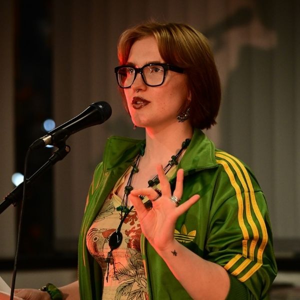 Poetry-Slammerin Heléne Grüning in einer grünen Adidas-Jacke mit Mikrofon