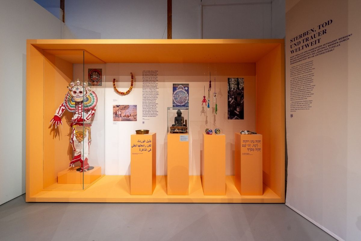 Ein tibetisches Totentanzkostüm mit Maske aus Textil und Pappmaché und andere Ausstellungsstücke im Freilichtmuseum Finsterau